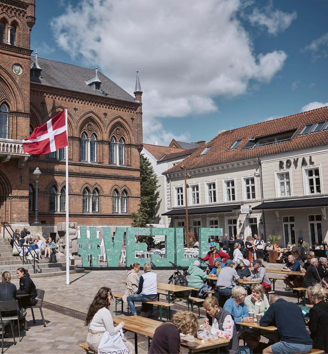 A group of people sitting at tables outside of a building. Description generated by AI