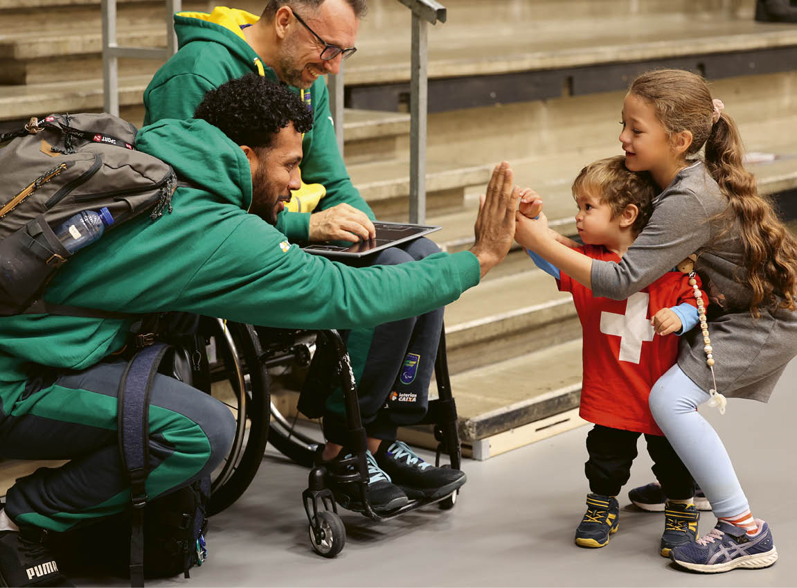 A man in a wheelchair is being high-fived by a young girl. Description generated by AI